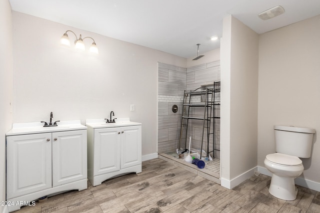 bathroom with toilet, wood-type flooring, vanity, and a tile shower