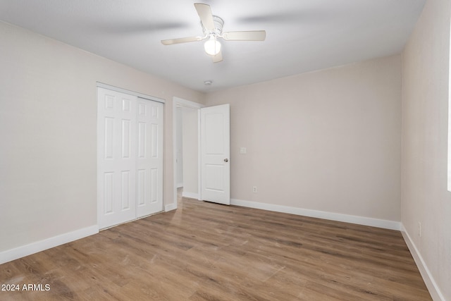 unfurnished bedroom with ceiling fan, wood-type flooring, and a closet