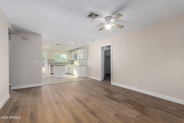 unfurnished living room with ceiling fan, wood-type flooring, and a textured ceiling