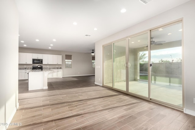 unfurnished living room featuring light wood finished floors, baseboards, ceiling fan, and recessed lighting