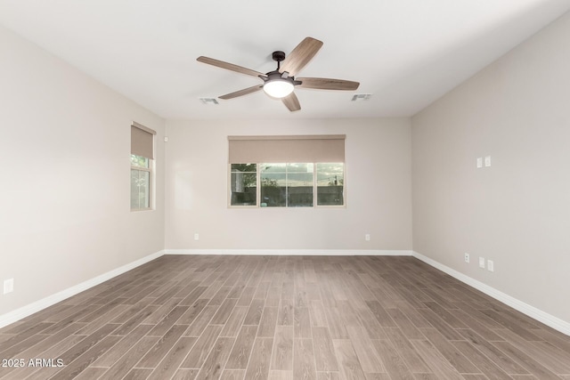 empty room with a ceiling fan, baseboards, visible vents, and wood finished floors