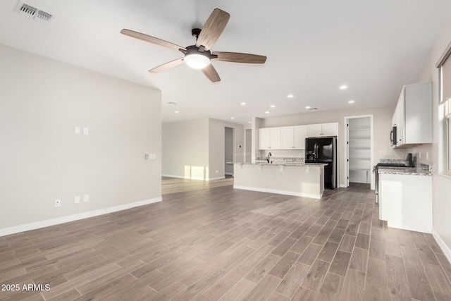 unfurnished living room with ceiling fan, baseboards, light wood finished floors, and visible vents