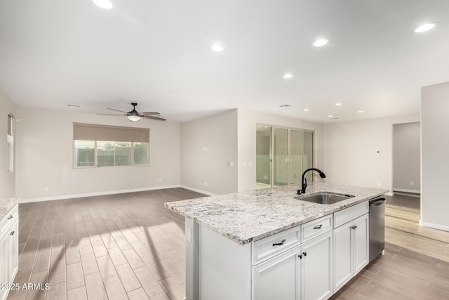 kitchen featuring a ceiling fan, dishwasher, baseboards, light wood finished floors, and a sink