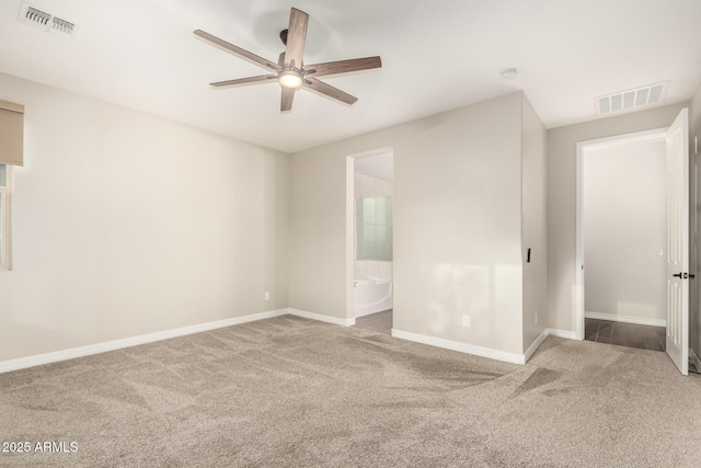 unfurnished bedroom with baseboards, ensuite bathroom, carpet flooring, and visible vents