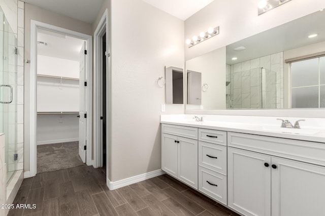 bathroom featuring a stall shower, a walk in closet, wood finish floors, and a sink