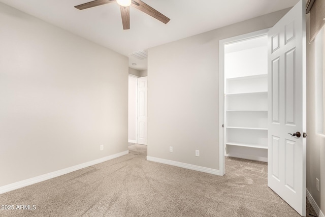 unfurnished bedroom with carpet flooring, a closet, baseboards, and a spacious closet
