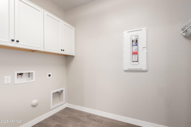 clothes washing area featuring baseboards, hookup for a washing machine, wood finished floors, hookup for an electric dryer, and cabinet space