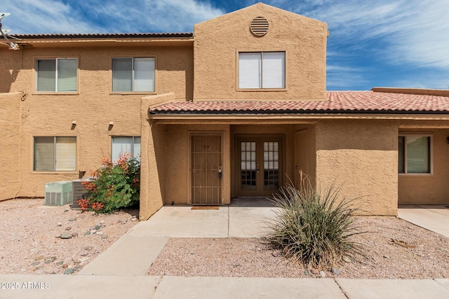 view of front of property with french doors, stucco siding, central AC, and a tile roof