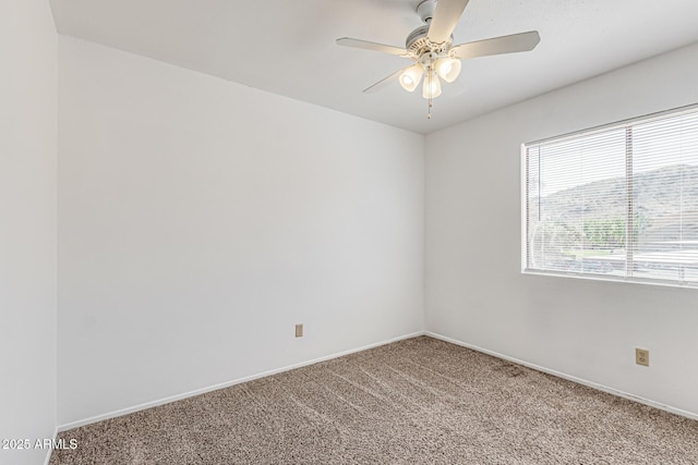 carpeted spare room featuring baseboards and a ceiling fan