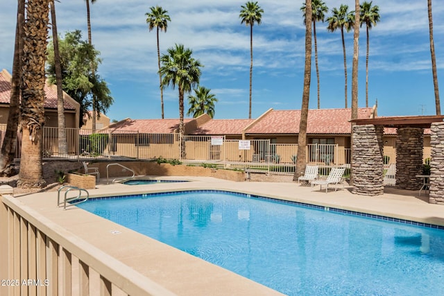 pool featuring fence, a community hot tub, and a patio area