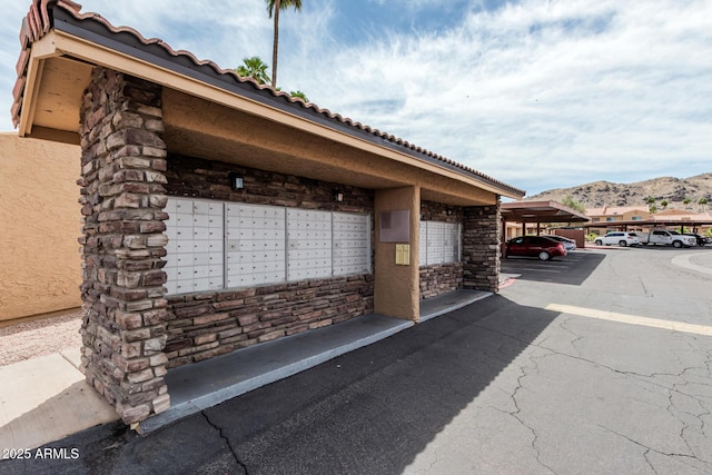 view of property's community featuring covered parking, a mountain view, and mail area