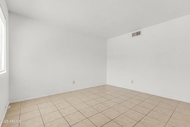 empty room with visible vents, baseboards, and light tile patterned floors