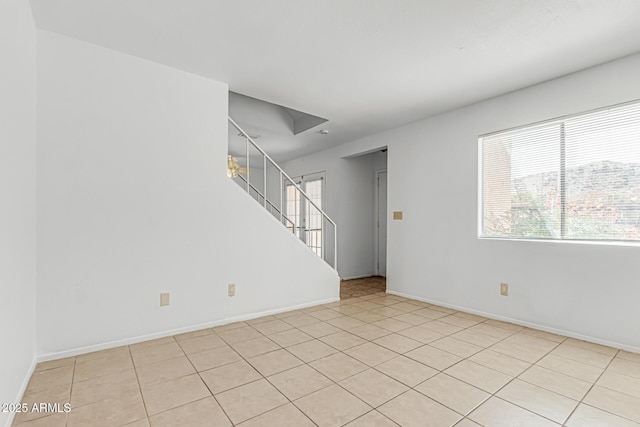 spare room featuring baseboards, stairs, and light tile patterned floors