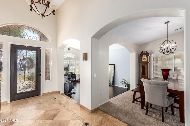 entryway with a towering ceiling, light tile patterned floors, and a notable chandelier