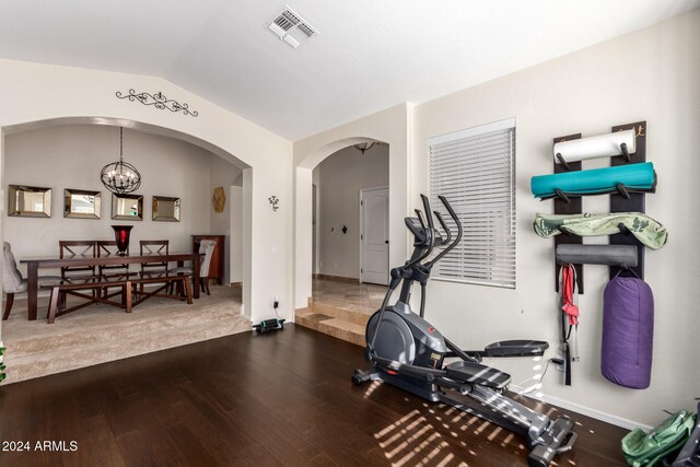 workout area with hardwood / wood-style floors, lofted ceiling, and an inviting chandelier