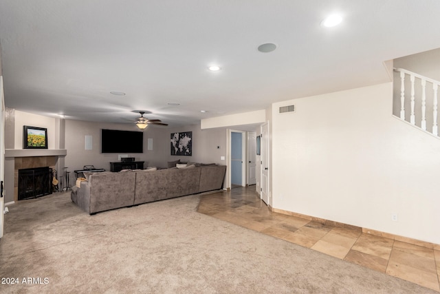 carpeted living room featuring a fireplace and ceiling fan