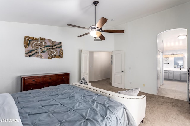 bedroom with light colored carpet, ceiling fan, vaulted ceiling, and connected bathroom