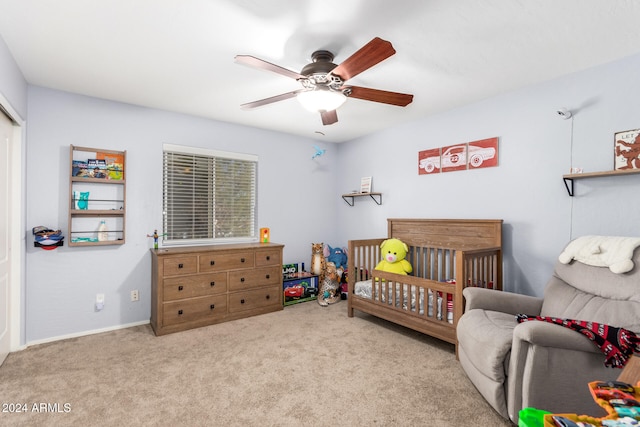 bedroom with ceiling fan, light carpet, and a nursery area