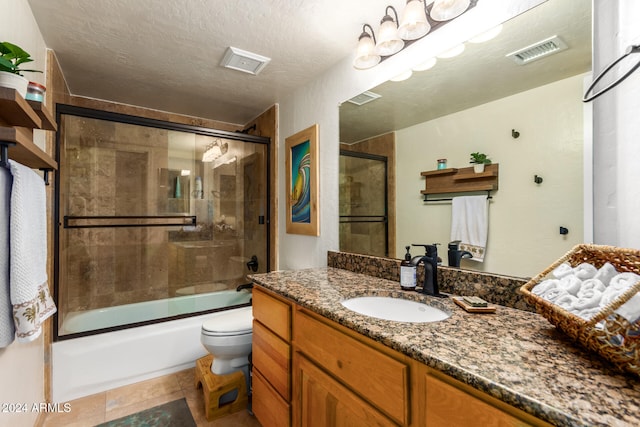 full bathroom featuring a textured ceiling, combined bath / shower with glass door, vanity, tile patterned floors, and toilet