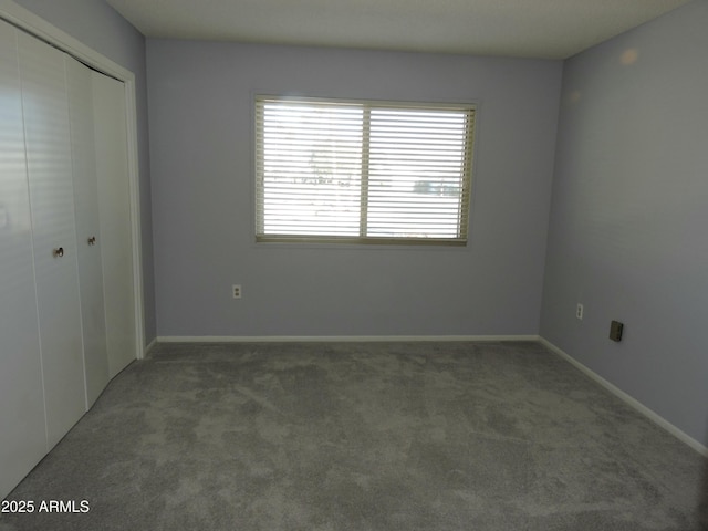 unfurnished bedroom featuring dark carpet and a closet