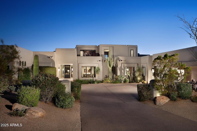 pueblo-style house featuring driveway and stucco siding