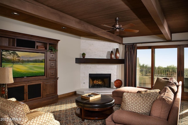 living area featuring beamed ceiling, wood finished floors, wooden ceiling, a fireplace, and ceiling fan