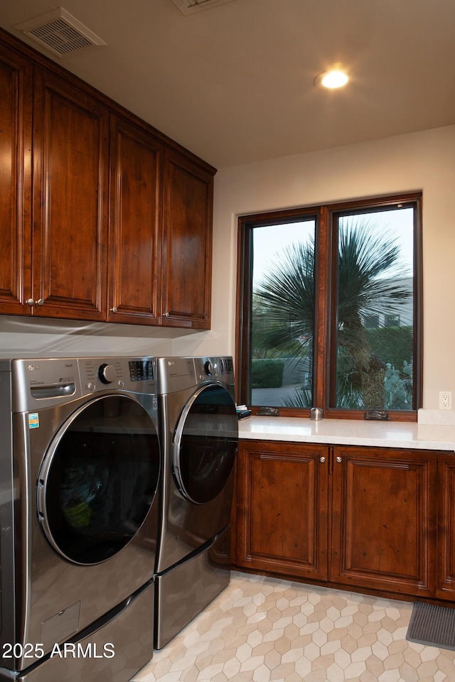 laundry area featuring cabinet space, washing machine and dryer, and visible vents