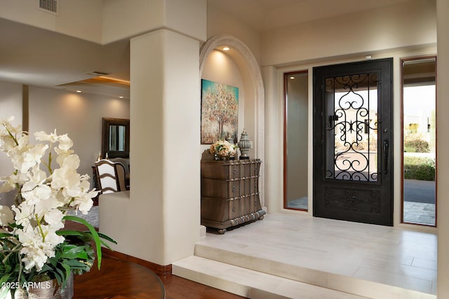 foyer entrance featuring visible vents, baseboards, and wood finished floors