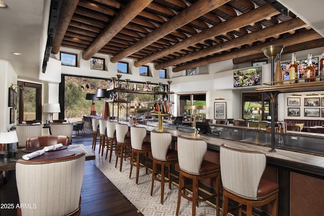 bar featuring wet bar, beam ceiling, and wood finished floors