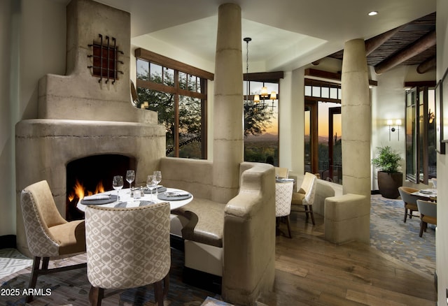 dining area featuring a chandelier, a fireplace, ornate columns, and wood-type flooring