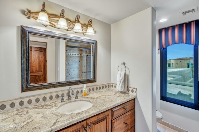 bathroom with vanity, toilet, and visible vents