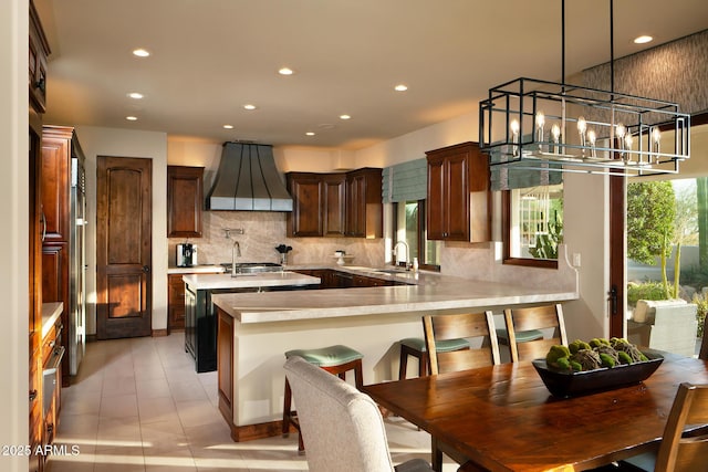 kitchen with backsplash, light countertops, recessed lighting, custom exhaust hood, and a sink