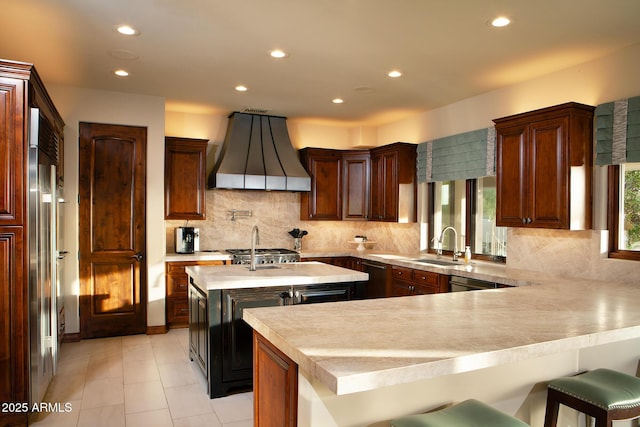 kitchen featuring premium range hood, a kitchen bar, a kitchen island with sink, recessed lighting, and light countertops