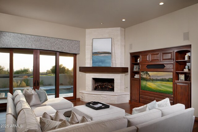 living room featuring recessed lighting, a stone fireplace, and dark wood-style flooring