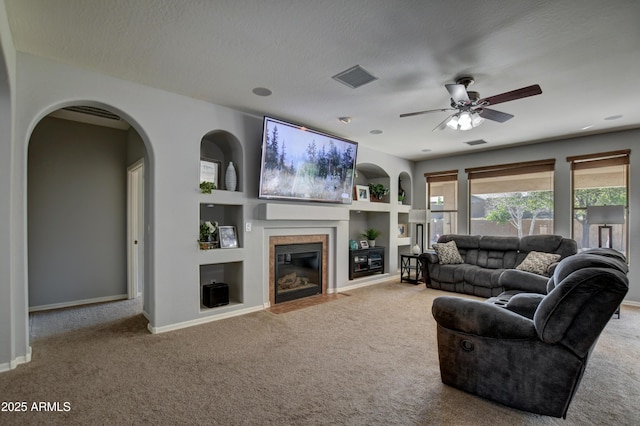 1527 Bainbridge Ln, Chino Valley, AZ 86323 - living area with carpet, a ceiling fan, a tile fireplace, baseboards, and arched walkways