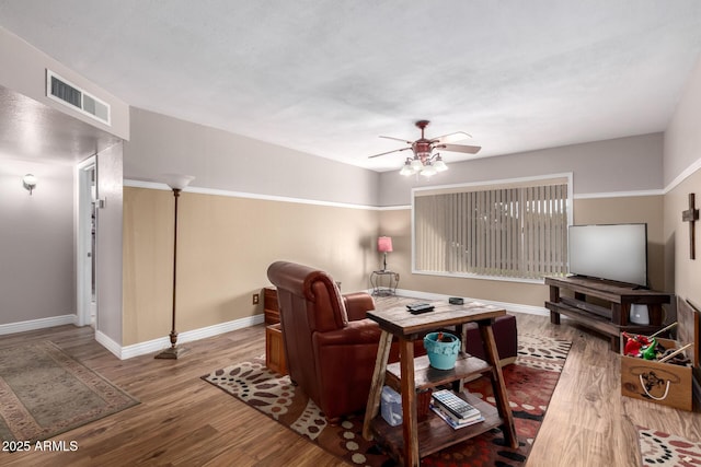 living room with visible vents, ceiling fan, baseboards, and wood finished floors