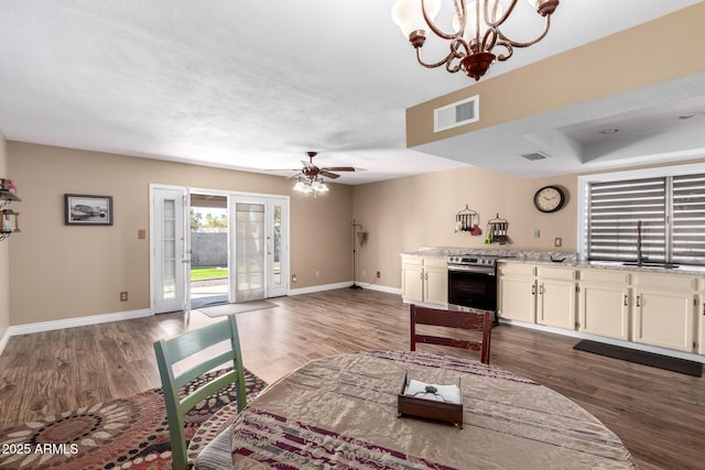 dining space with dark wood-style floors, baseboards, visible vents, and ceiling fan with notable chandelier