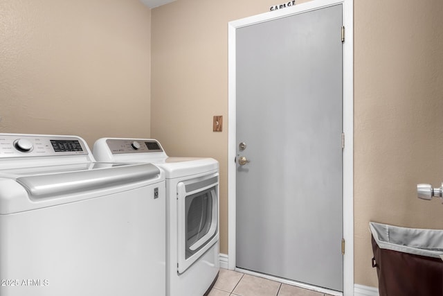 washroom featuring laundry area, washer and clothes dryer, and light tile patterned floors