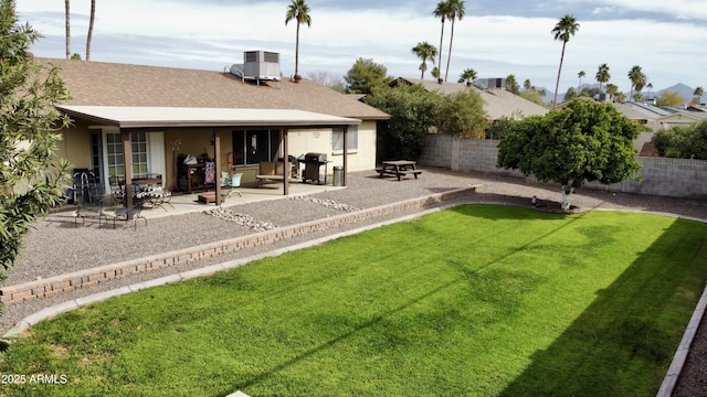 back of property featuring a shingled roof, a patio, a fenced backyard, cooling unit, and a yard