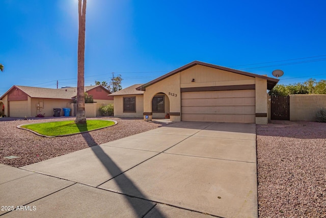 ranch-style home with a garage, driveway, fence, and stucco siding