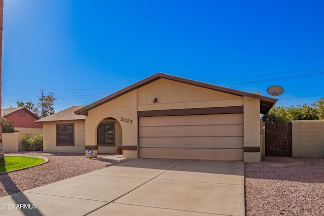 ranch-style home with stucco siding, a shingled roof, concrete driveway, an attached garage, and fence