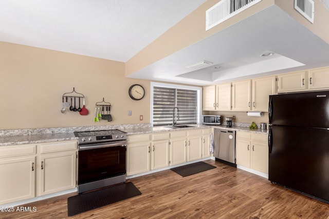 kitchen with visible vents, appliances with stainless steel finishes, wood finished floors, a tray ceiling, and a sink