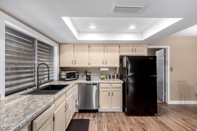 kitchen with stainless steel appliances, a raised ceiling, visible vents, a sink, and light wood-type flooring