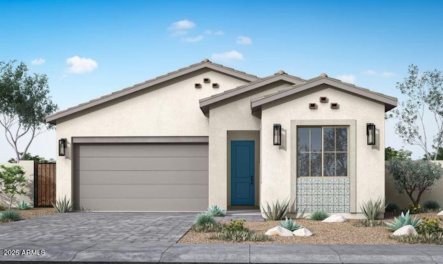 view of front of house with decorative driveway, fence, a garage, and stucco siding