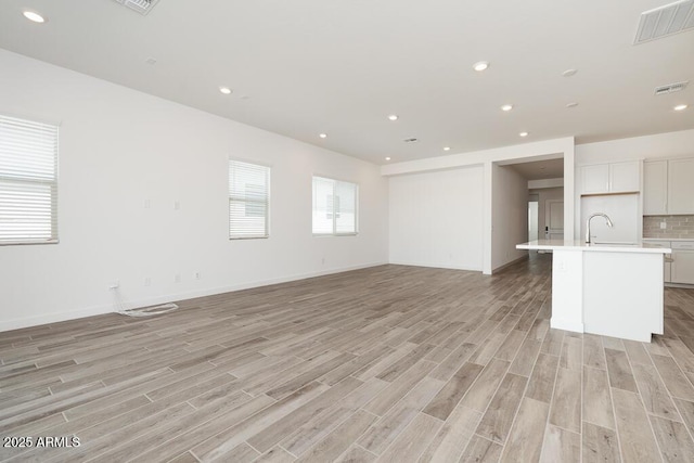 352 E Las Perlas Ln, San Tan Valley, AZ 85140 - unfurnished living room with light wood-type flooring, a sink, recessed lighting, and baseboards