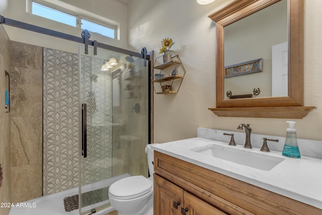 bathroom featuring a shower with shower door, toilet, and vanity