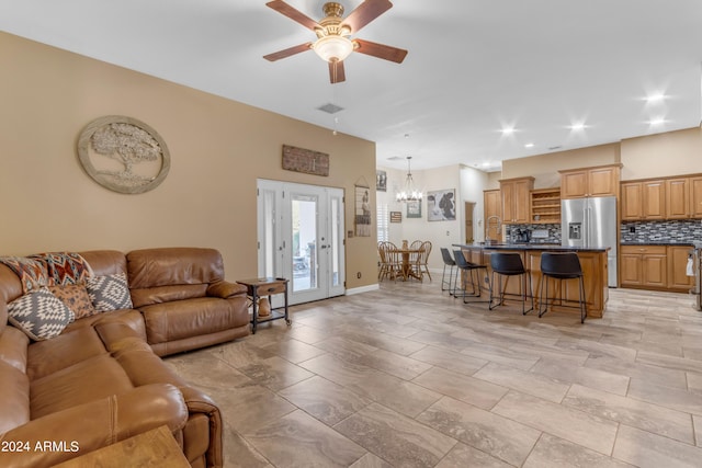 living room featuring ceiling fan with notable chandelier and sink