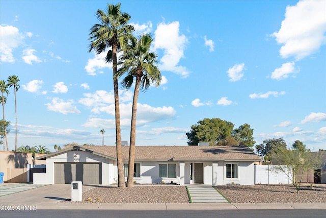 ranch-style house featuring driveway, an attached garage, fence, and stucco siding