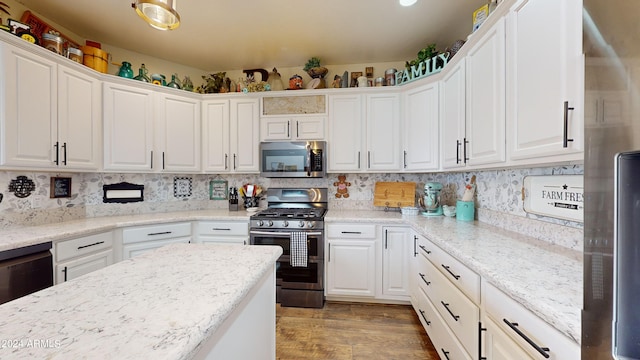 kitchen with light stone countertops, white cabinetry, light wood-type flooring, stainless steel appliances, and tasteful backsplash