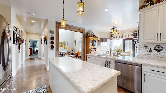 kitchen with pendant lighting, sink, light stone counters, appliances with stainless steel finishes, and light hardwood / wood-style floors